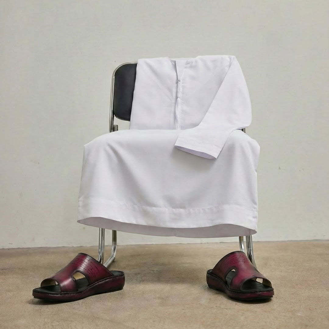 White Kandura draped on a chair with sandals underneath.